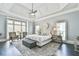 A luxurious main bedroom with a tray ceiling, sitting area, and large windows for natural light at 3233 Bagley Psge, Duluth, GA 30097