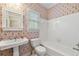 Bathroom featuring a pedestal sink, patterned wallpaper, white fixtures, and a shower-tub combo at 1272 Saxony Se Dr, Conyers, GA 30013