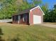 Detached brick garage on a well-manicured lawn, with a white picket fence on the property at 1272 Saxony Se Dr, Conyers, GA 30013