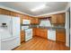 A well-lit kitchen features white appliances, hardwood floors, and wooden cabinetry at 4715 Hill Rd, Powder Springs, GA 30127