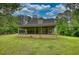 This spacious backyard with a porch, lush green grass, and mature trees at 1761 Mcdaniel Mill Rd Sw, Conyers, GA 30094