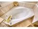 A luxurious soaking tub with gold fixtures and tile surround at 1761 Mcdaniel Mill Rd Sw, Conyers, GA 30094
