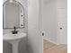 Stylish bathroom featuring a pedestal sink, arched mirror and modern fixtures at 5086 Cumberland Ct, Villa Rica, GA 30180