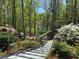 View of backyard with stairs leading to lake, lush landscaping, mature trees, and inviting seating area at 6255 Lakeview Dr, Buford, GA 30518