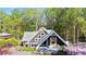 Charming home with gray facade, unique geometric windows and covered porch surrounded by lush landscaping and mature trees at 6255 Lakeview Dr, Buford, GA 30518
