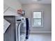 Convenient laundry room featuring a modern washer and dryer, storage shelving, and a bright window at 11210 Easthaven Pl, Duluth, GA 30097