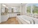 Bathroom featuring granite countertop, a soaking tub, ample cabinet space, and a large window with outdoor views at 2156 Fairway Cir, Duluth, GA 30096