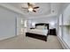 Spacious main bedroom featuring a ceiling fan, tray ceiling, and a view to the bathroom at 3870 Cabalzar St, Cumming, GA 30040