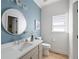 Stylish powder room features a modern vanity, round mirror and light blue accent wall at 648 Gold Valley Pass, Canton, GA 30114