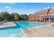 Beautiful community pool with lounge chairs, umbrellas, and mature trees offering shade and a large clubhouse at 6414 Blue Water Dr, Buford, GA 30518