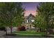 Charming brick home with manicured lawn, mature trees, and inviting front porch at dusk at 6414 Blue Water Dr, Buford, GA 30518