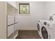 Bright laundry room featuring modern appliances, tiled floor, and a storage shelving at 3840 Wieuca Ne Ter, Atlanta, GA 30342