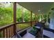 Covered porch with wood railings, tile floors, wicker furniture, and views of lush green trees and backyard at 3840 Wieuca Ne Ter, Atlanta, GA 30342