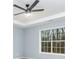 Bright bedroom featuring a ceiling fan, tray ceiling, and a view of surrounding woods at 319 Primrose Ln, Auburn, GA 30011