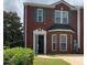 Brick townhome with green shutters and a bay window, surrounded by lush greenery and a well-maintained lawn at 5897 Strathmoor Manor Cir, Lithonia, GA 30058