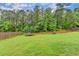 Expansive backyard with lush green grass, a trampoline, and mature trees at 3419 Mulberry Cove Way, Auburn, GA 30011