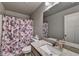 Bathroom with granite countertop, framed mirror, toilet, and a shower with a floral curtain at 3419 Mulberry Cove Way, Auburn, GA 30011