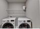 Bright laundry room equipped with a washer, a dryer, and a storage shelf at 3419 Mulberry Cove Way, Auburn, GA 30011