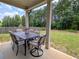 Covered outdoor patio with cushioned seating, a table, and views of the green yard at 3419 Mulberry Cove Way, Auburn, GA 30011
