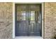 Close-up of an elegant gray double front door with glass panels and brick surround at 1631 Manhasset Dr, Atlanta, GA 30338