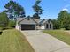 View of the home with a 2-car garage, set on a well-maintained lawn and long driveway at 7171 Hazelwood Dr, Jonesboro, GA 30236