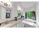 Primary bathroom featuring double sinks, granite countertop, large window, and soaking tub at 829 Verdun Way, Marietta, GA 30064