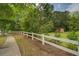 A serene backyard enclosed by a white fence featuring a lush, green lawn with trees and a charming storage shed at 1670 Cooper Lakes Dr, Grayson, GA 30017