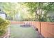 Fenced backyard with green grass, chairs around a fire pit, and tall trees surrounding the perimeter at 2019 Chelton Se Way, Smyrna, GA 30080