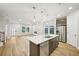 Open-concept kitchen and living room featuring a large island, stainless steel appliances, and light hardwood flooring at 4680 Hemingway Trl, Cumming, GA 30041