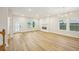 Spacious living room with a modern fireplace, light hardwood floors, and ample natural light from large windows at 4680 Hemingway Trl, Cumming, GA 30041