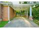 Carport featuring brick columns, a metal gate, and a concrete driveway leading to a brick house with green foliage at 698 N Superior Ave, Decatur, GA 30033
