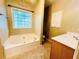 Bright bathroom features a soaking tub under a window, separate vanity area, and neutral color palette at 25 Derby Dr, Hiram, GA 30141