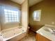 Bright bathroom features a soaking tub under a window, separate vanity area, and neutral color palette at 25 Derby Dr, Hiram, GA 30141