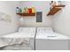 Functional laundry room includes a washer, dryer, shelving, and all necessary electrical panel access at 9186 Puckett St, Covington, GA 30014