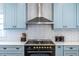 Close up of the light blue kitchen cabinets, stainless vent hood and tiled backsplash with gold accents at 333 Mimosa Dr, Decatur, GA 30030