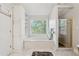 Bright bathroom featuring a soaking tub under a window and a separate glass-enclosed shower at 2849 Shiaway Trl, Snellville, GA 30039