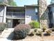 Exterior of a two-story condo featuring stone accents, a small deck, and well-maintained landscaping at 4018 Woodridge Way, Tucker, GA 30084