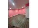 Unfinished basement with pink walls, laminate floors, recessed lighting, and a white door at 4685 Trefoil Path, Cumming, GA 30040