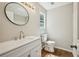 Updated bathroom with a modern vanity, round mirror, and a window for natural light at 5126 Farm Place Ne Dr, Woodstock, GA 30188