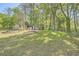 Large, lush backyard with mature trees, green grass, and storage buildings at 4201 Regal Ridge Rd, Austell, GA 30106