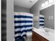 Cozy bathroom features a striped shower curtain, modern vanity, and neutral wall color at 9988 Devonshire St, Douglasville, GA 30135