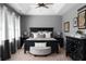 Serene main bedroom featuring a stylish bed, dresser, and ottoman, complemented by neutral colors and soft lighting at 9988 Devonshire St, Douglasville, GA 30135