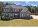 Two-story home featuring a manicured lawn, gray siding, stone accents, and a welcoming covered front porch at 524 Trousseau Ln, Mcdonough, GA 30252