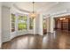 Elegant dining room featuring a bay window, chandelier, and dark wood floors, open to the library at 550 Vinings Springs Se Dr, Mableton, GA 30126