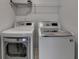 Laundry room featuring modern, front-loading, white washer and dryer with metal storage shelf above at 2272 Misty Brook Ct, Buford, GA 30519