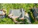 Aerial view of a brick home featuring a well-manicured lawn, mature trees, and a paved driveway at 415 Oak Laurel Ct, Johns Creek, GA 30022