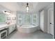 Bright bathroom with a large soaking tub, tiled floors and a view of the trees at 415 Oak Laurel Ct, Johns Creek, GA 30022