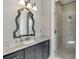 Bathroom featuring granite countertops, decorative mirror, and glass door shower at 6050 Eagle Close Ln, Sugar Hill, GA 30518