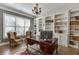 Charming home office with a large window, chandelier, hardwood floors, built-in bookshelves, and a desk at 6050 Eagle Close Ln, Sugar Hill, GA 30518