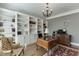 Comfortable home office with a large window, chandelier, hardwood floors, built-in bookshelves, and a desk at 6050 Eagle Close Ln, Sugar Hill, GA 30518